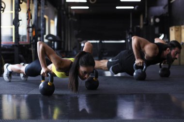 Spor salonunda şınav çeken kadın ve erkek.