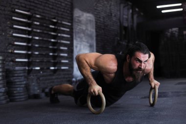 Sportif Hintli güçlü adam halkalarla şınav çekiyor.