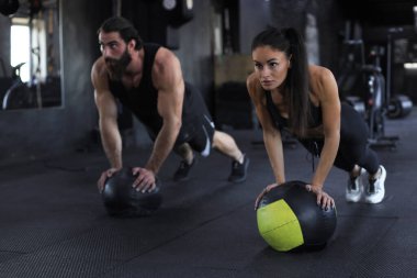 Güzel Hintli genç spor çifti spor salonunda sağlık topuyla antrenman yapıyor.
