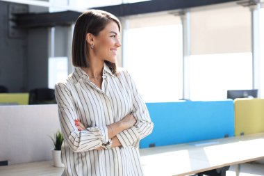 Çekici iş kadını gündelik kıyafetlerini giyer, başka yere bakar ve ofiste gülümserdi..