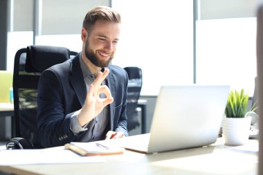 Gülümseyen genç iş adamı ofiste video görüşmesi yapıyor.