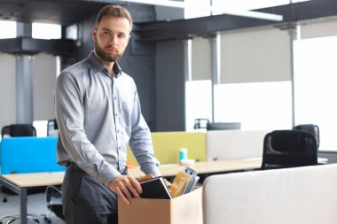 Üzgün işçi ofis malzemelerini yanında götürüyor.