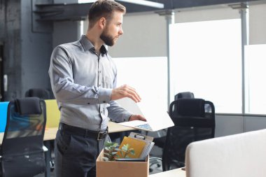 Üzgün işçi ofis malzemelerini yanında götürüyor.