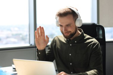 Gülümseyen genç iş adamı ofiste video görüşmesi yapıyor.