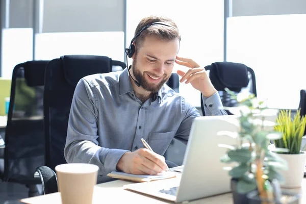 Uśmiechnięty Operator Call Center Słuchawkami Siedzącymi Nowoczesnym Biurze Przeglądający Informacje — Zdjęcie stockowe