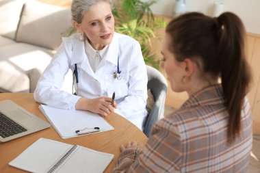 Ofisteki hastaya danışmanlık yapan orta yaşlı kadın doktor.