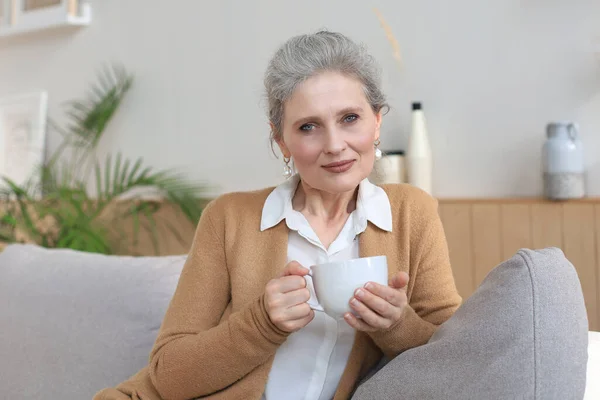 Mujer Madura Feliz Descansando Sofá Cómodo Beber Café Mira Cámara — Foto de Stock