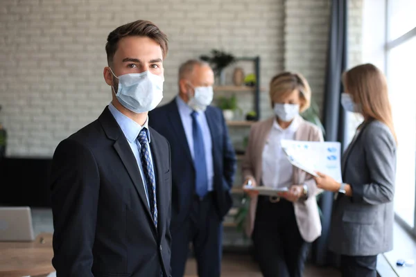 Empresario Máscara Médica Con Colegas Fondo Oficina —  Fotos de Stock