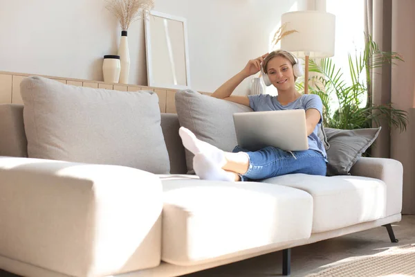 Lächelnde Junge Frau Mit Kopfhörer Und Laptop Auf Dem Sofa — Stockfoto
