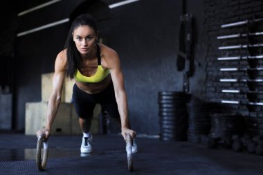 Sportif Hintli güçlü kadın halkalarla şınav çekiyor.