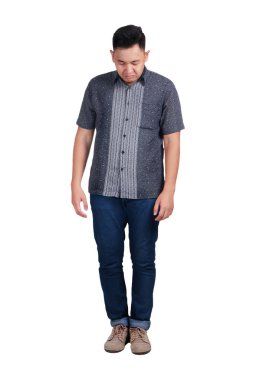 Mavi jeans ve aşağı bakıyor batik forması giyen üzgün Genç Asyalı adam. Beyaz izole. Tam vücut portre