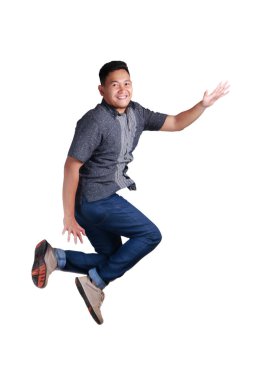 Mavi jeans ve batik forması giyen havada, yürüyüş mutlu Genç Asyalı adam. Beyaz izole. Tam vücut portre.