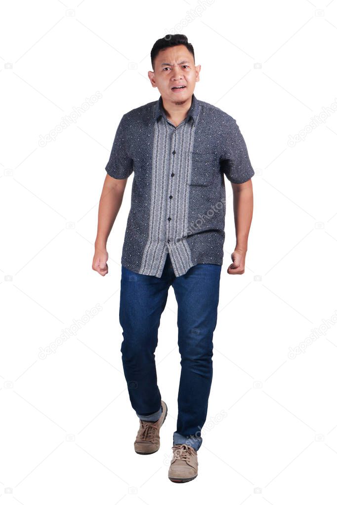 Angry young Asian man waering batik, standing and looking forward, ready to fight, isolated on white