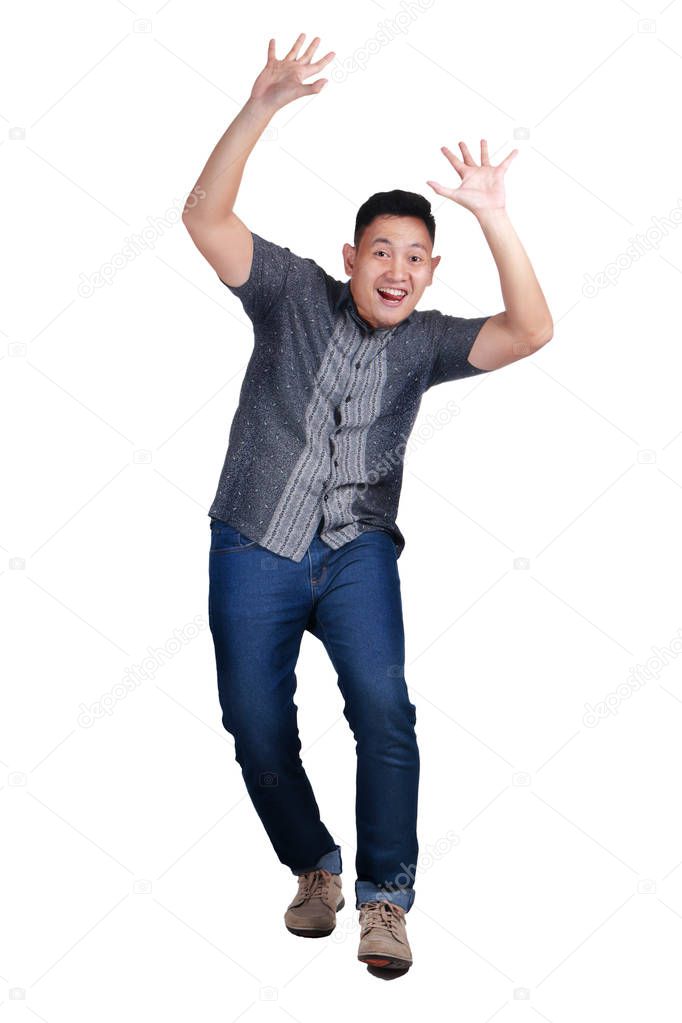 Young Asian man wearing blue jeans and batik shirt, dancing happily gesture. Isolated on white. Full  body portrait
