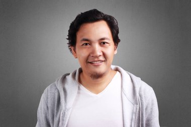 Bir ceket, kameraya bakarak gülen kendine güvenen Genç Asyalı adam