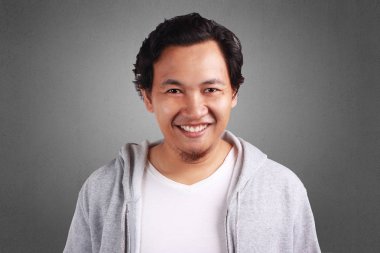 Mutlu bir şekilde ifade gülümseyen beyaz gömlek ve gri ceket giyen genç Asyalı adam. Arka plan gri. Baş ve omuz kapatın