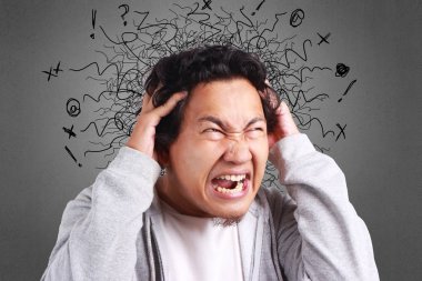 Gömlek ve gri ceket bir baş ağrısı olan sinirli giyen genç Asyalı adam ifade stres. Arka plan gri. Baş ve omuzlar kapatın