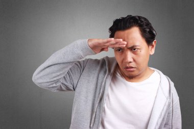 Genç Asyalı Erkek Ceket çok ilerisinde bakın; Süre çatık; Bir şey ararken