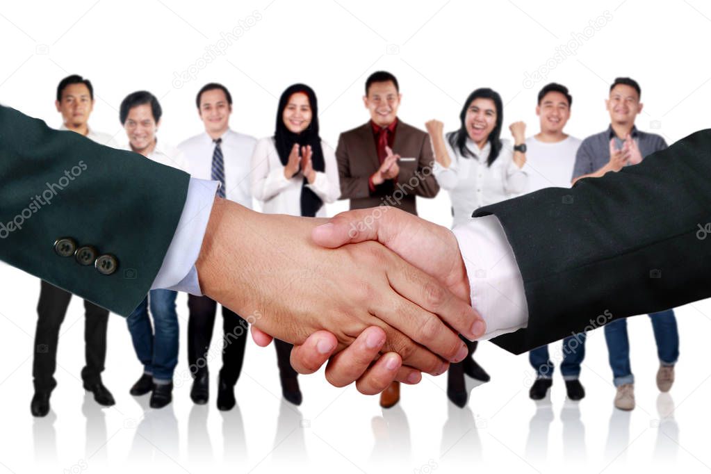 Close up image of businessmen doing handshake for having deal. Agreement partnership in business concept. With group of team work people behind. Focus on foreground. Blurred background