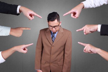 Accusation guilty business person. Asian businessman get upset with many fingers pointing at him over grey background  clipart