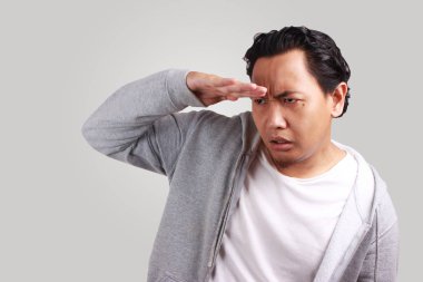 Genç Asyalı Erkek Ceket çok ilerisinde bakın; Süre çatık; Bir şey ararken