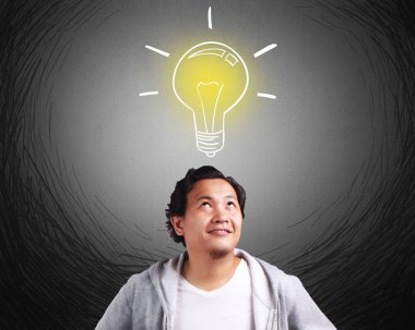 Bir fikir olan ceket giyen genç Asyalı adam gözleri üstünde, başının üzerinde ampul ile bakış