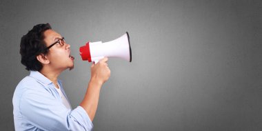 Küçük Asya megafon, kızgın ifade kullanarak giyen beyaz ve mavi gömlek bağıran adam. Vücut portre kadar kapatın