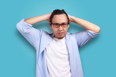 Jest flört, saç dokunmadan ve gülümseyen, mavi duvar arka plan üzerinde gözlük ile komik emin Asyalı adam 