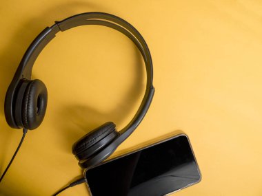 Kulaklık ve smartphone. Kulaklık turuncu zemin üzerine. Hareket eden telefon aygıt kavramı üzerinde ses müzik dinleme