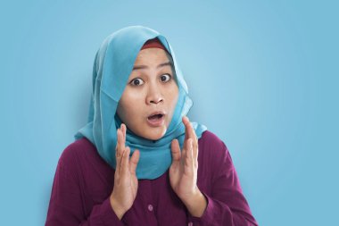 Üzerinde mavi arka plan açık ağız ile sürpriz hijab giyen güzel Asya Müslüman kadın portresi 