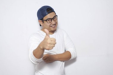 Fotoğraf resim portre komik çekici şirin Asyalı gencin gülümseyen ve başparmak tabela duran beyaz arka plan üzerinde gösterilen beyaz gömlekli