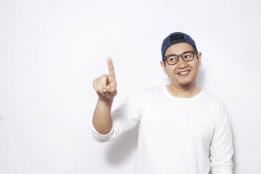 Genç Asyalı adam giyen beyaz gömlek gözlük ve hatpointing ifade gülümseyen ile ileriye doğru. Vücut portre, kopya alanı ile beyaz duvara kadar kapatın