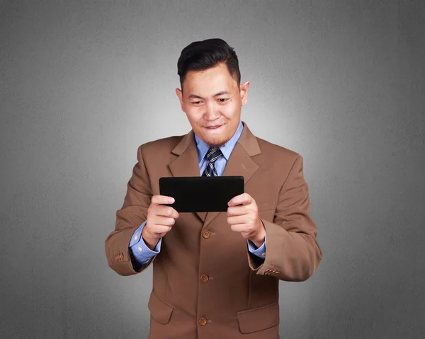 Portrait of happy young Asian businessman playing on his tablet, surfing browsing good news, online games, leisure activity, over grunge background