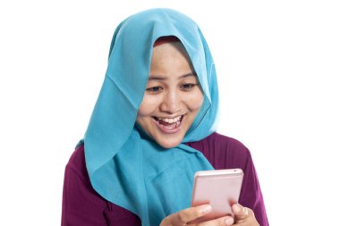 Mutlu Asyalı Müslüman kadının portresi. Mesajı okurken gülümsüyor. Akıllı telefonundan iyi haberler geliyor.
