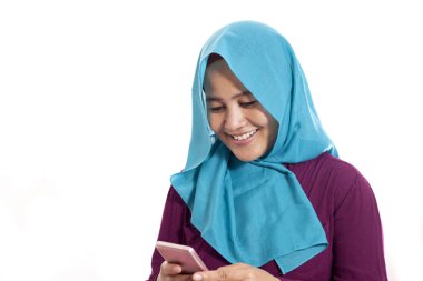 Mutlu Asyalı Müslüman kadının portresi. Mesajı okurken gülümsüyor. Akıllı telefonundan iyi haberler geliyor.