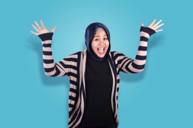 Başarı portresi zafer jest mavi arka plan üzerinde kazanan ile gülüyor hijab giyen güzel Müslüman kadın