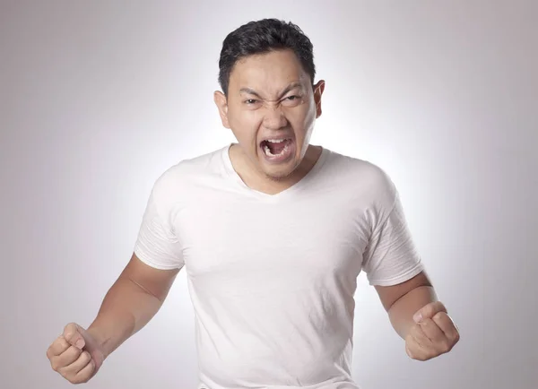 アジア系の若い男は怒りのため叫んでいる白いシャツ着て 灰色の背景 頭と肩を閉じる — ストック写真