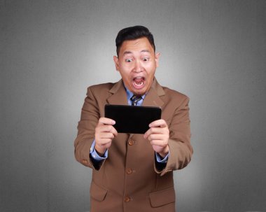 Fotoğraf görüntü bir tablet, başarılı kazanan jest tutarken kutluyor zafer çığlıkları sevimli yakışıklı bir genç Asyalı adam portresi