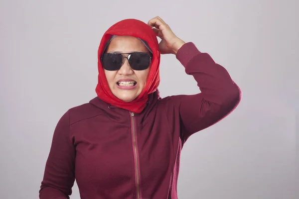 赤いスーツとヒジャーブに黒のサングラスをかけてアジアのイスラム教徒の女性の肖像画は 心配して神経質になってジェスチャーを示しています 彼女の頭部を傷付け — ストック写真