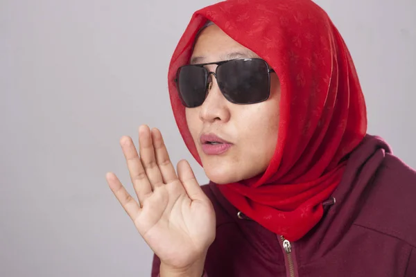 亚洲穆斯林夫人的肖像穿着黑色太阳镜在红色西装和头巾告诉一些秘密 窃窃私语手势 八卦骗局新闻概念 — 图库照片