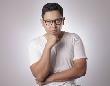 Küçük Asya adam giyiyor rahat beyaz gömlek düşünce, ifade gülümseyen. Vücut portre kadar kapatın