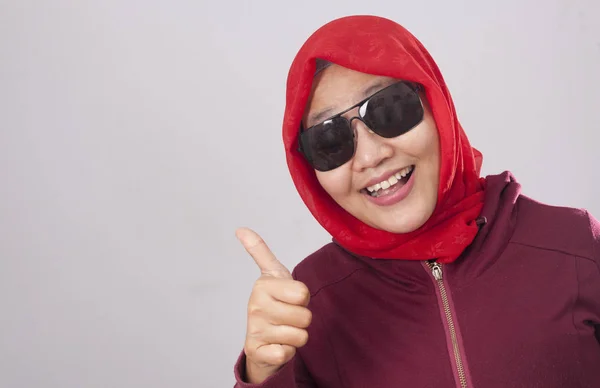 穿着红色西装戴着黑色太阳镜的年轻亚洲穆斯林女士的肖像显示着大拇指的手势 微笑着快乐的脸 批准确定的标志 — 图库照片