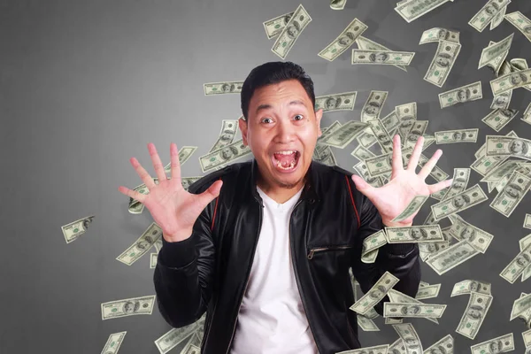 Portrait of happy successful young Asian billionaire man smiling happily under rain of money. Wealth investment economic concept