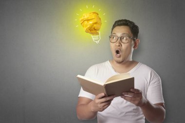 Kağıttan, fikir ve yenilik sembolü yapılmış parlak ampul lamba ile mutlu gülümseyerek başarılı yakışıklı Asya adam portresi