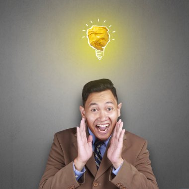 Kağıttan, fikir ve yenilik sembolü yapılmış parlak ampul lamba ile mutlu gülümseyerek başarılı yakışıklı Asya adam portresi