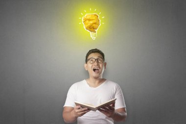 Kağıttan, fikir ve yenilik sembolü yapılmış parlak ampul lamba ile mutlu gülümseyerek başarılı yakışıklı Asya adam portresi