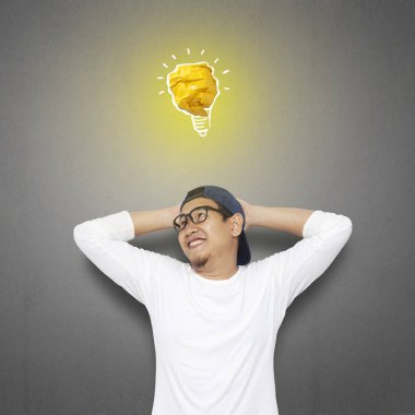 Kağıttan, fikir ve yenilik sembolü yapılmış parlak ampul lamba ile mutlu gülümseyerek başarılı yakışıklı Asya adam portresi