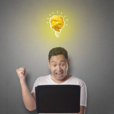 Kağıttan, fikir ve yenilik sembolü yapılmış parlak ampul lamba ile mutlu gülümseyerek başarılı yakışıklı Asya adam portresi