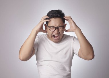 Küçük Asya öfke yüzünden giyen beyaz gömlek bağıran adam. Arka plan gri. Baş ve omuzlar kapatın