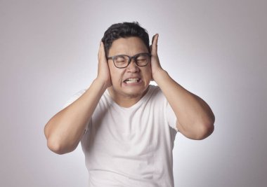 Portrait of young Asian man wearing casual white shirt closing his eyeas and ears dont want or avoiding to hear bad news, stress under mental pressure concept